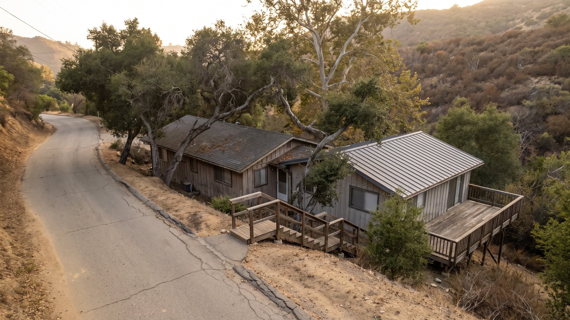 Hillside houses below a one-lane road in Topanga Canyon, oaks overhanging the roofs