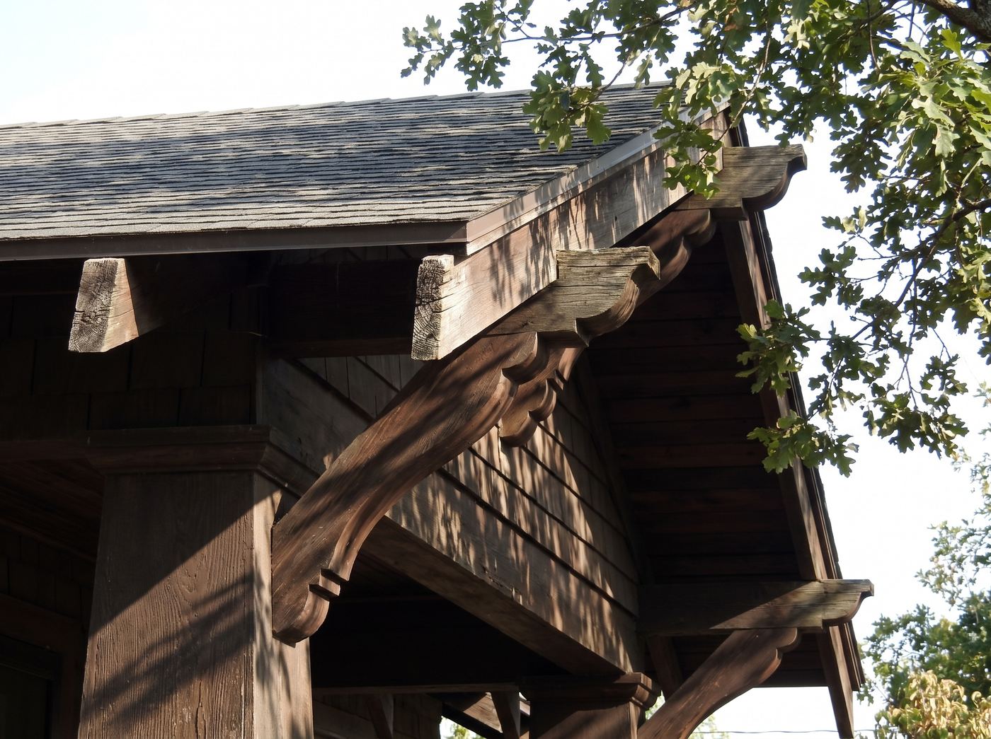 A Craftsman eave with decorative rafter tails and knee braces below a low-pitch roof
