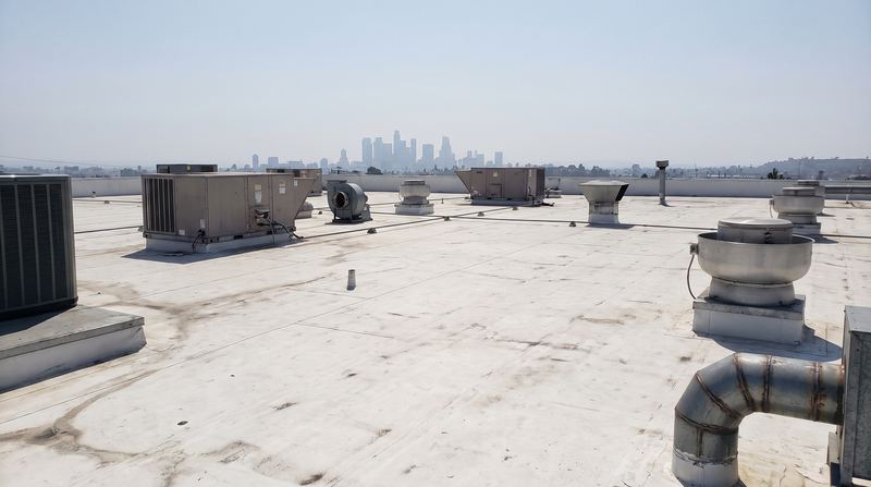 A flat commercial roof deck in white TPO membrane